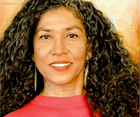woman with long curly hair wearing a red top, and smiling
