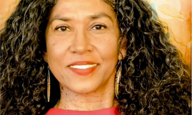 woman with long curly hair wearing a red top, and smiling